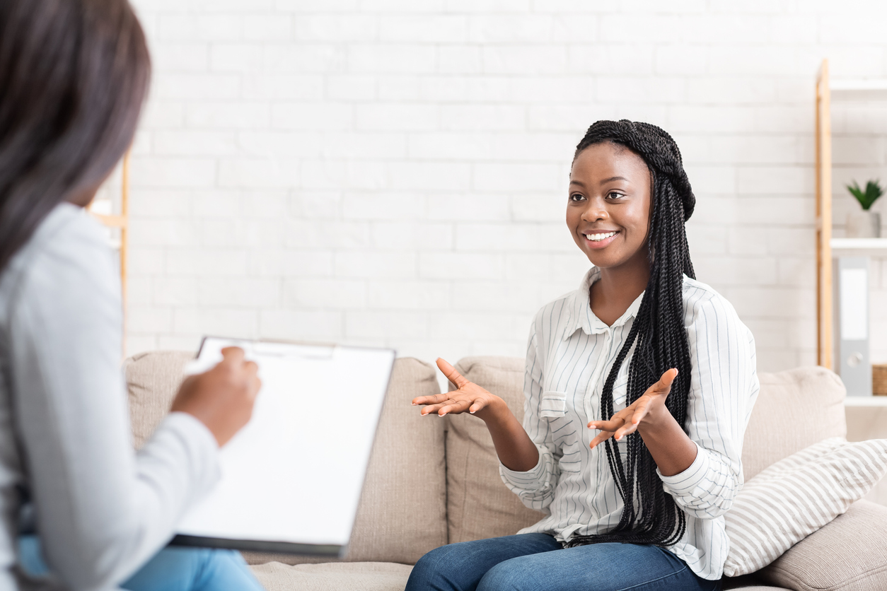 Successful therapy. Happy black female patient talking to psychologist at her office, expressing gratitude